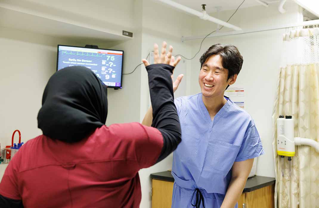 Two people high-fiving in a hospital setting