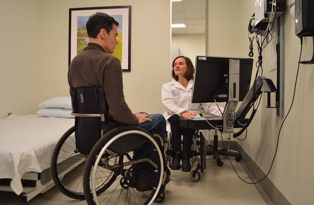 Dr. Cheri Blauwet and a patient, both in wheelchairs, in a medical examination room for a doctor-patient consult
