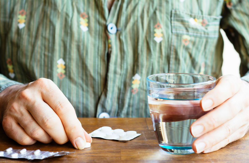 A man in pajamas takes a pill.