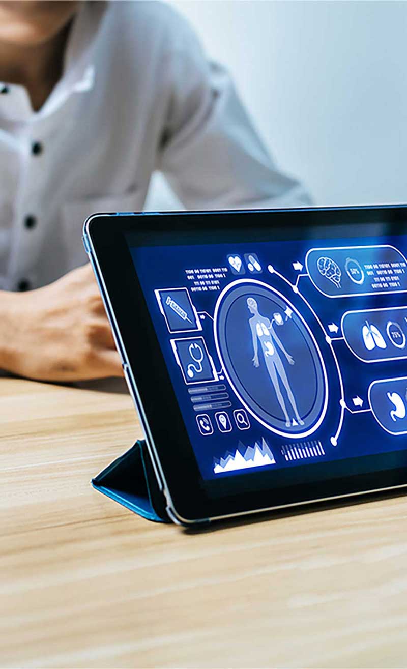 A person sitting behind a standing tablet, with a medical interface on the tablet screen.