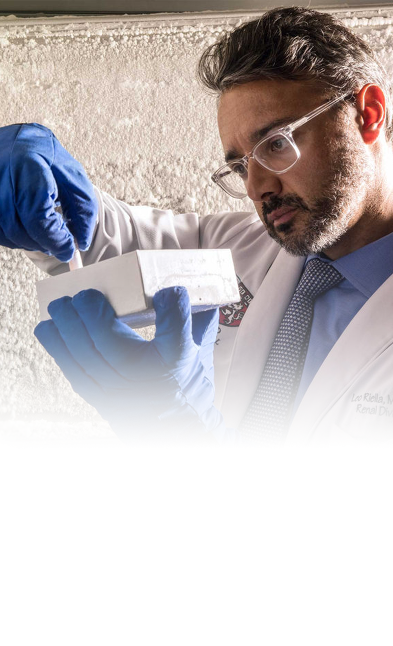 A doctor examines a vial that he lifts from a box.
