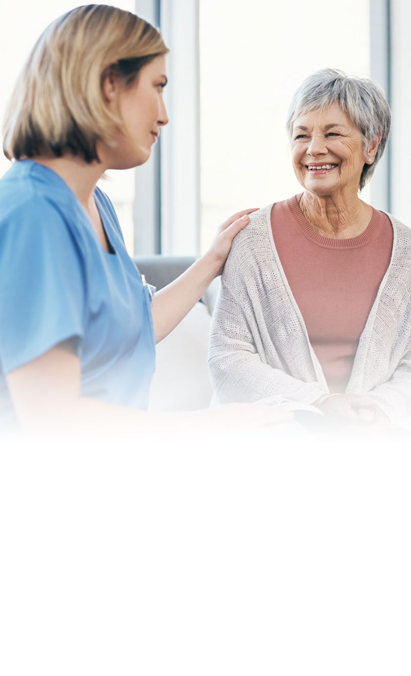 female provider with hand on shoulder of smiling older female patient