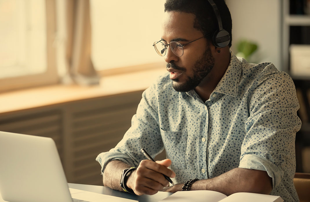 A man holding a pen works in front of a laptop