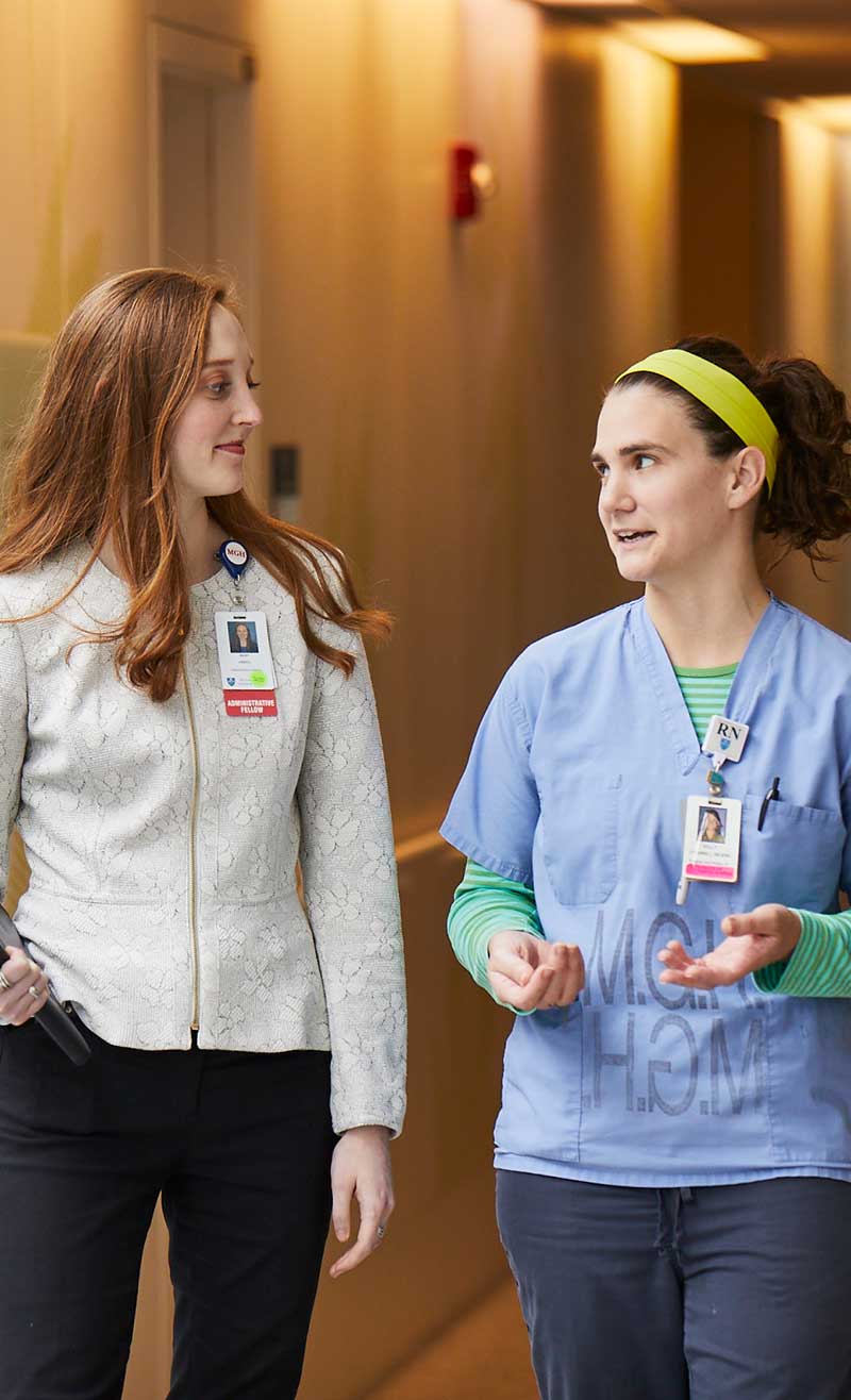 A nurse and an administrative fellow conferring in a hospital hallway.
