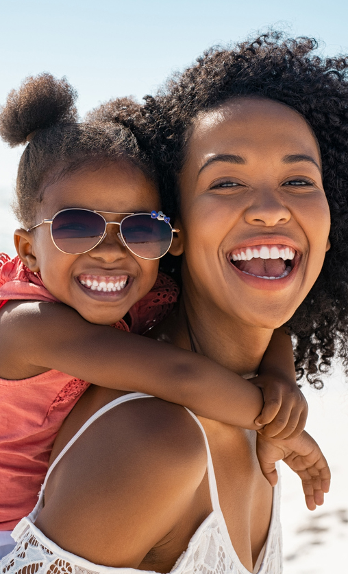 Mom and daughter on beach smiling