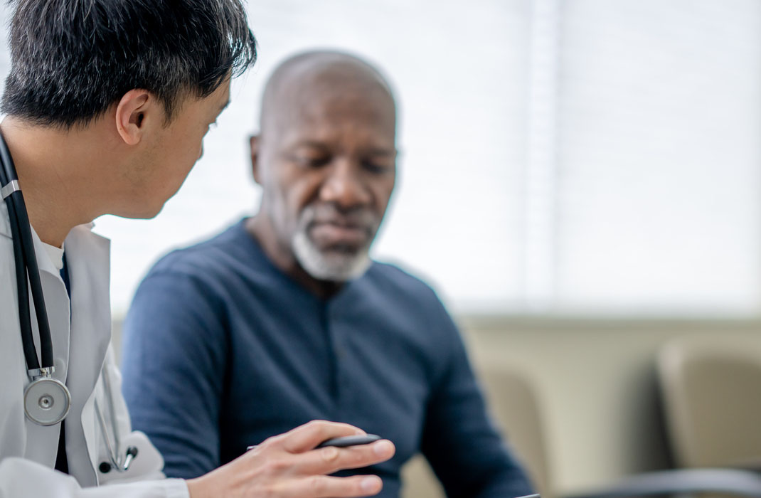 Senior man talking with doctor and looking at tablet