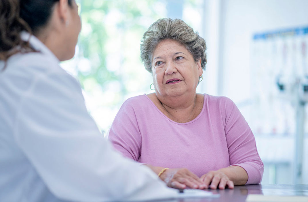 female provider talking to older female patient in exam room