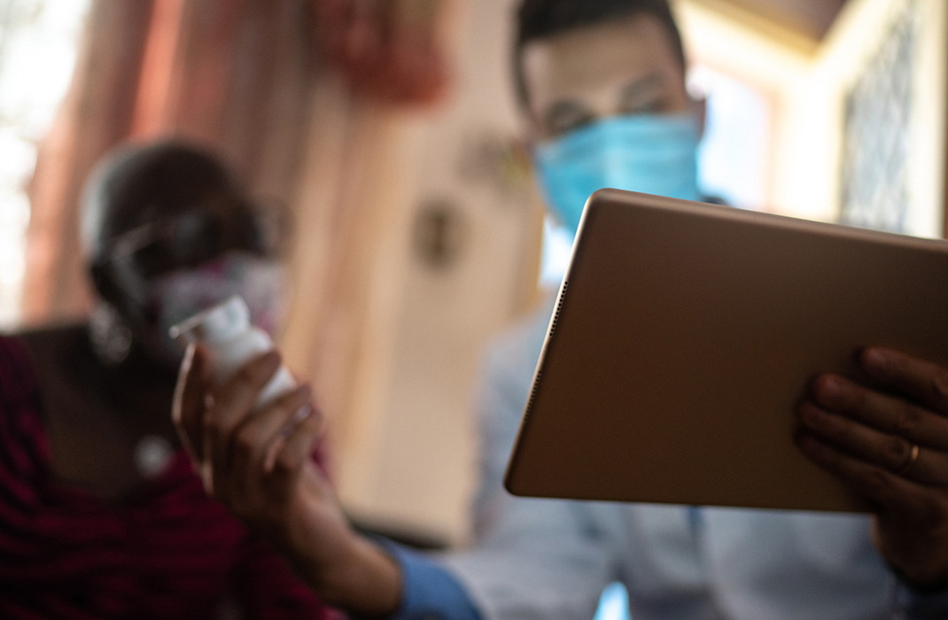 medical provider holding a tablet for a patient in their home