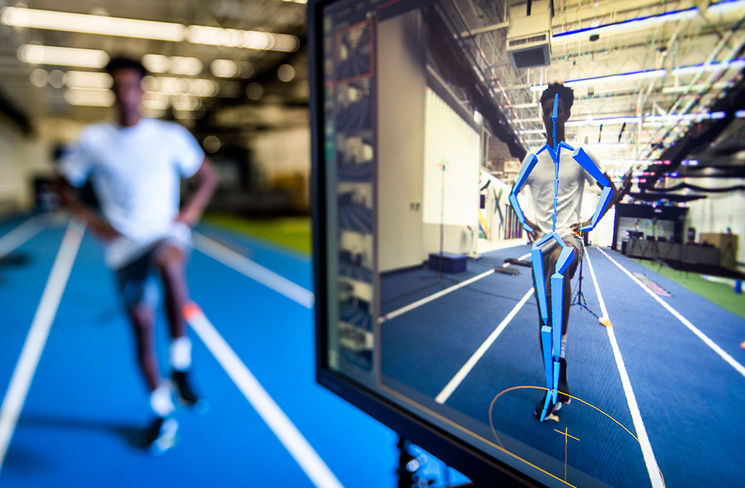 male athlete walking on track while undergoing testing connected to monitor