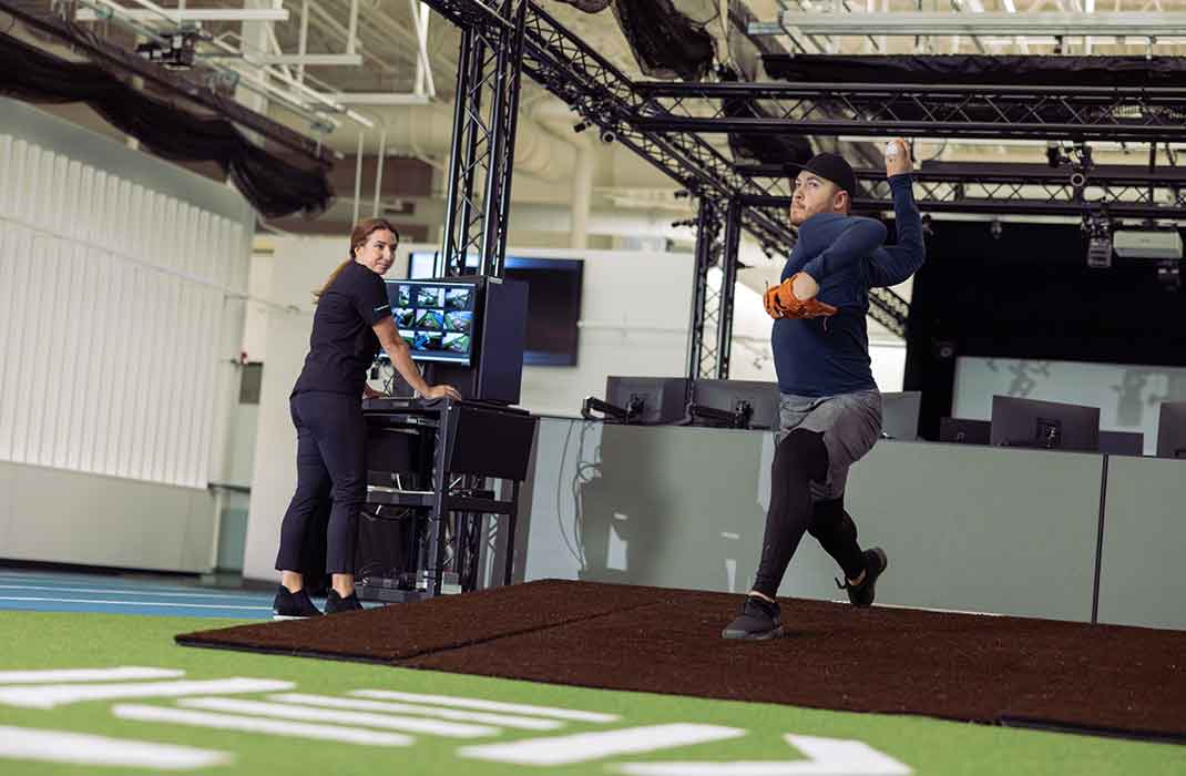 male athlete throwing a baseball in gym during a pitching assessment