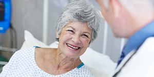 older woman in hospital gown talking to provider