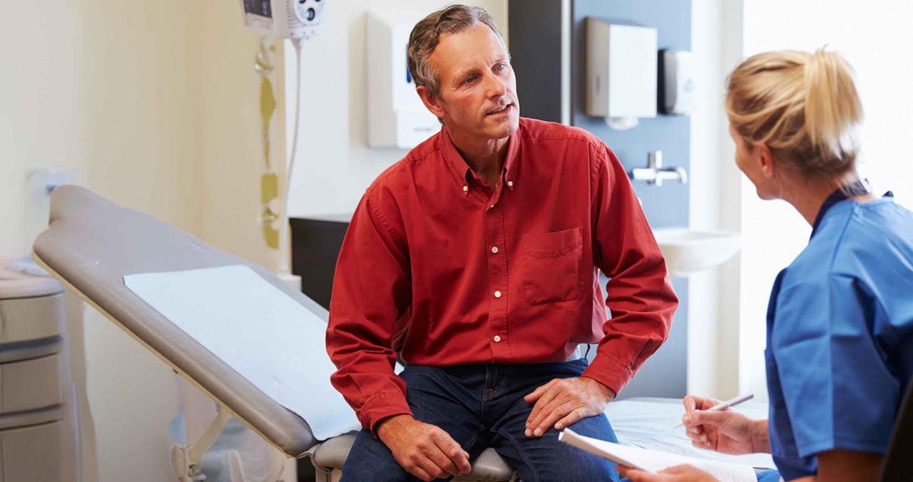 man talking with female clinician in exam room
