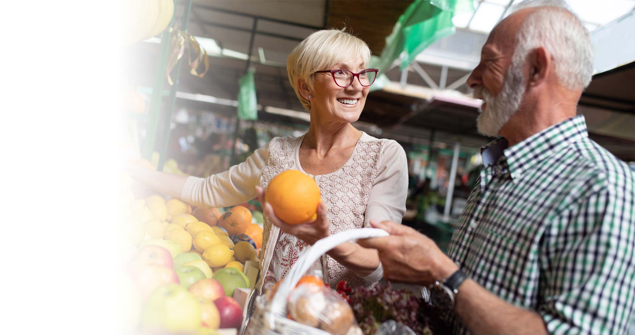 Senior couple shopping for fresh fruit at market