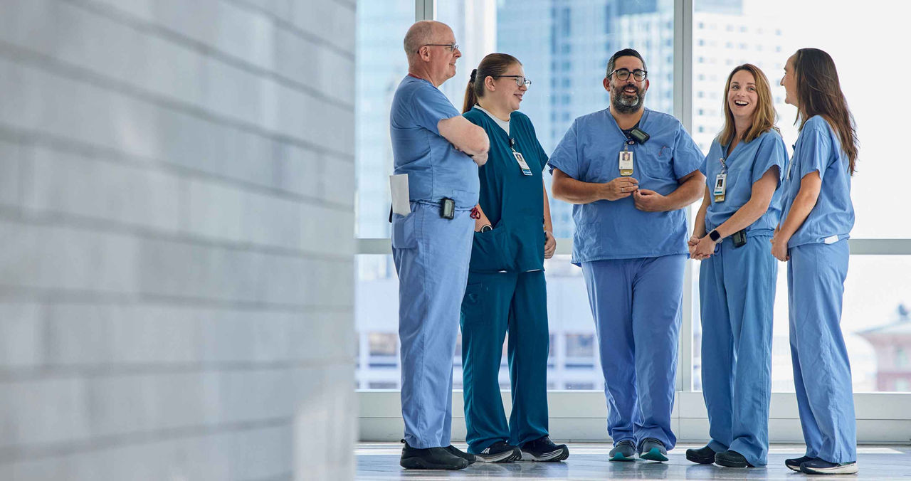 group of clinicians in scrubs talking in hallway