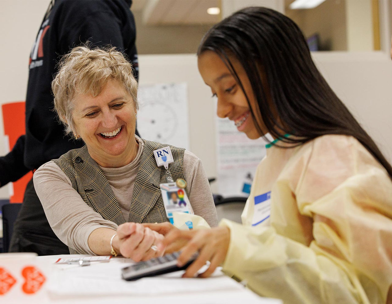 Two people smiling and having an educational discussion about science in a classroom setting
