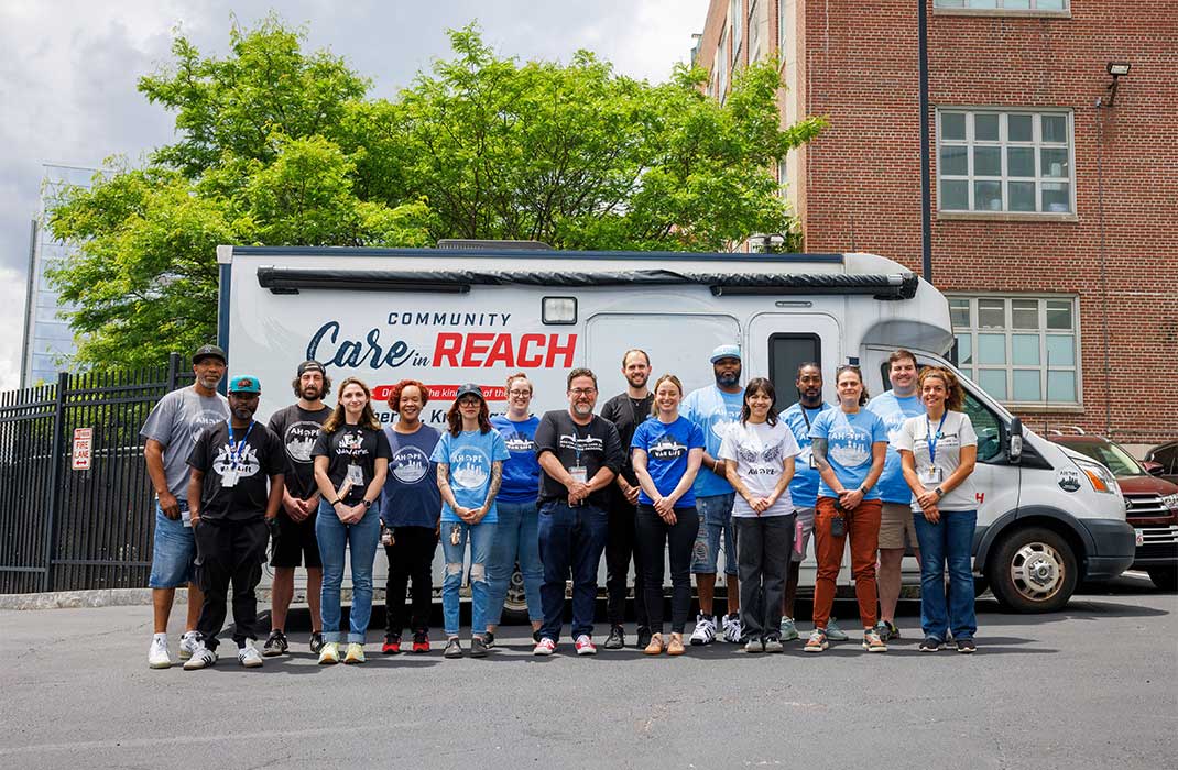 Boston Health Care for the Homeless Program  team standing outside the Community Care in Reach mobile unit, committed to bringing service around the Boston area.