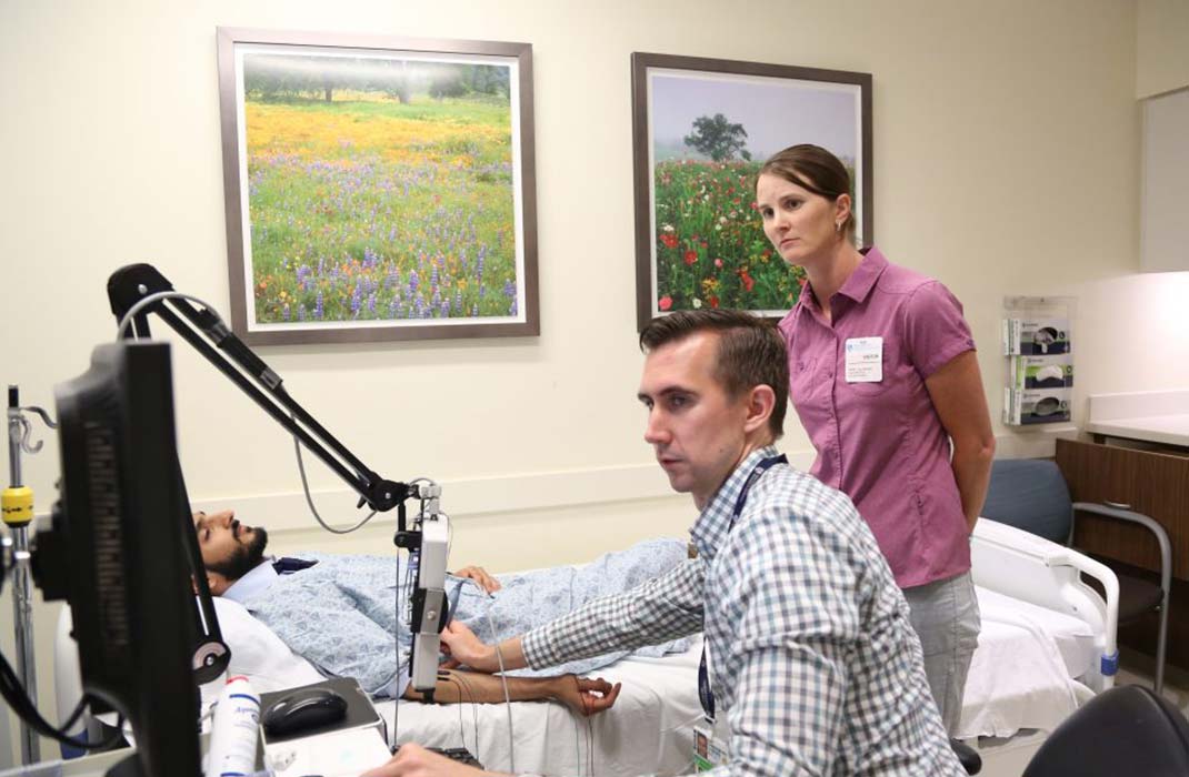 A doctor provides medical skills training to a health provider with a volunteer on a hospital bed