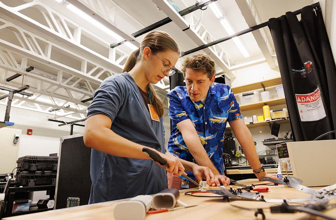 male researcher watching female student in laboratory