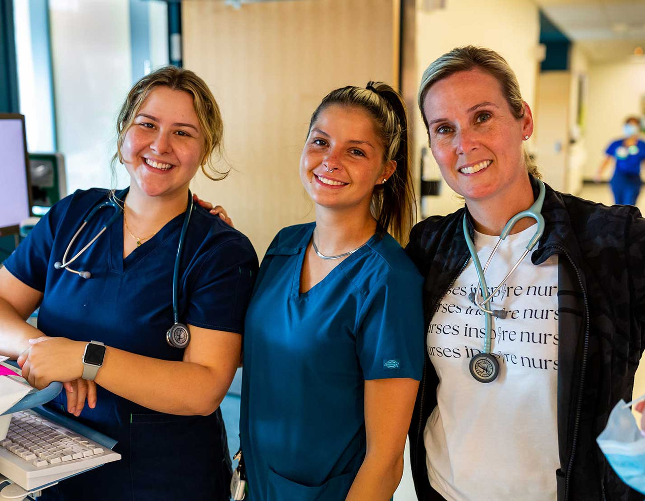 three female nurses smiling in hallway