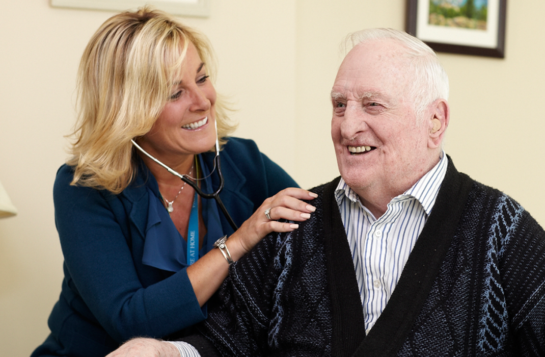 female medical professional using stethoscope on elderly man