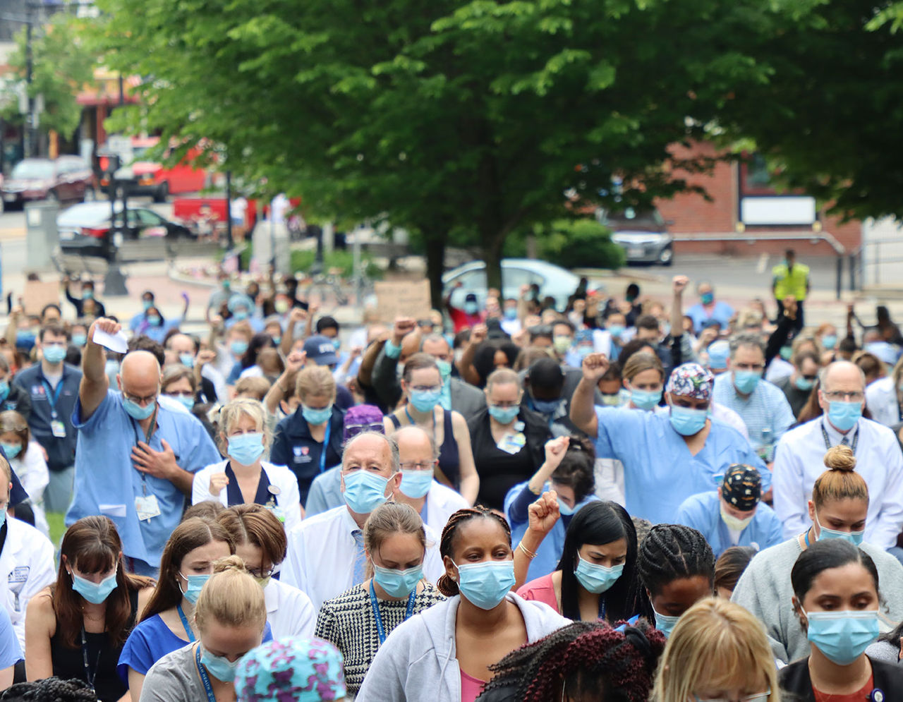 Clinicians in masks, raising arms for United Against Racism 