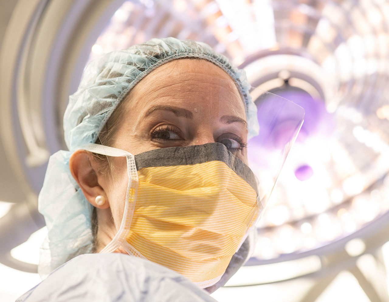 female surgeon with mask and face shield in operating room