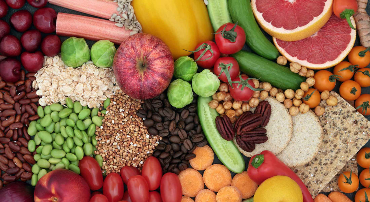 A spread of healthy foods including vegetables, nuts, seeds, and fruits