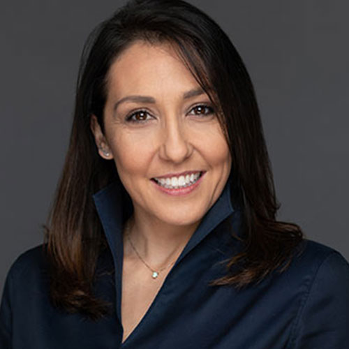 A professional woman with shoulder-length brown hair is depicted wearing a navy shirt with a collar.