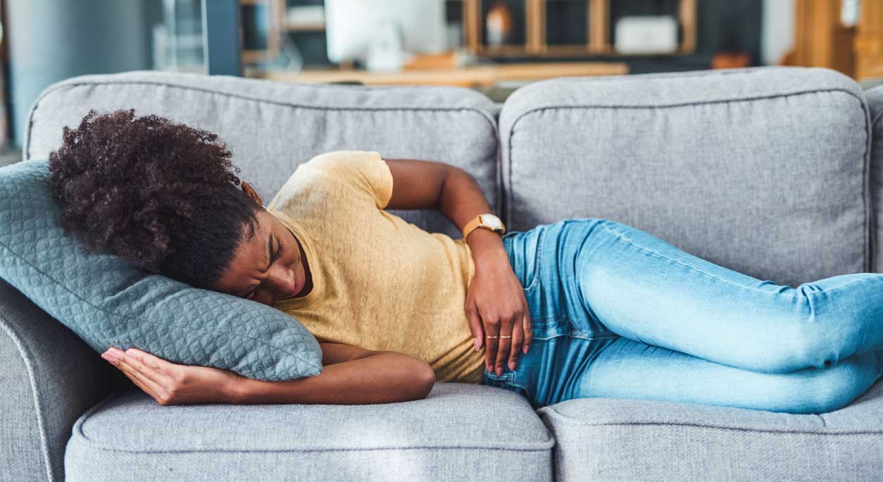 A woman with abdominal pain lies on the couch.