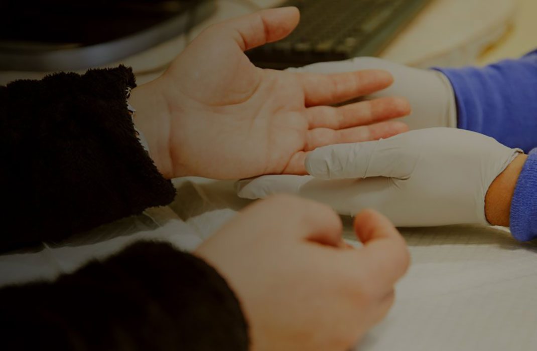 a gloved doctor's hand holding a patient's hand