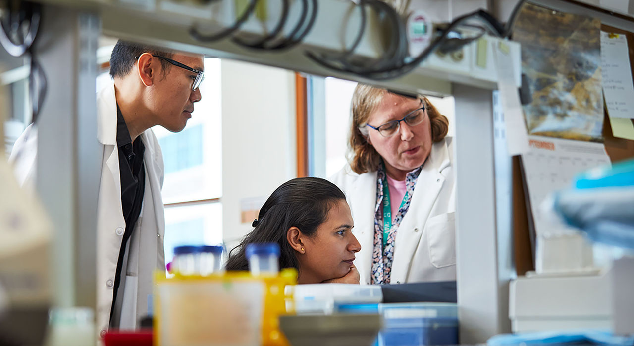 Three doctors reading a document in a lab 