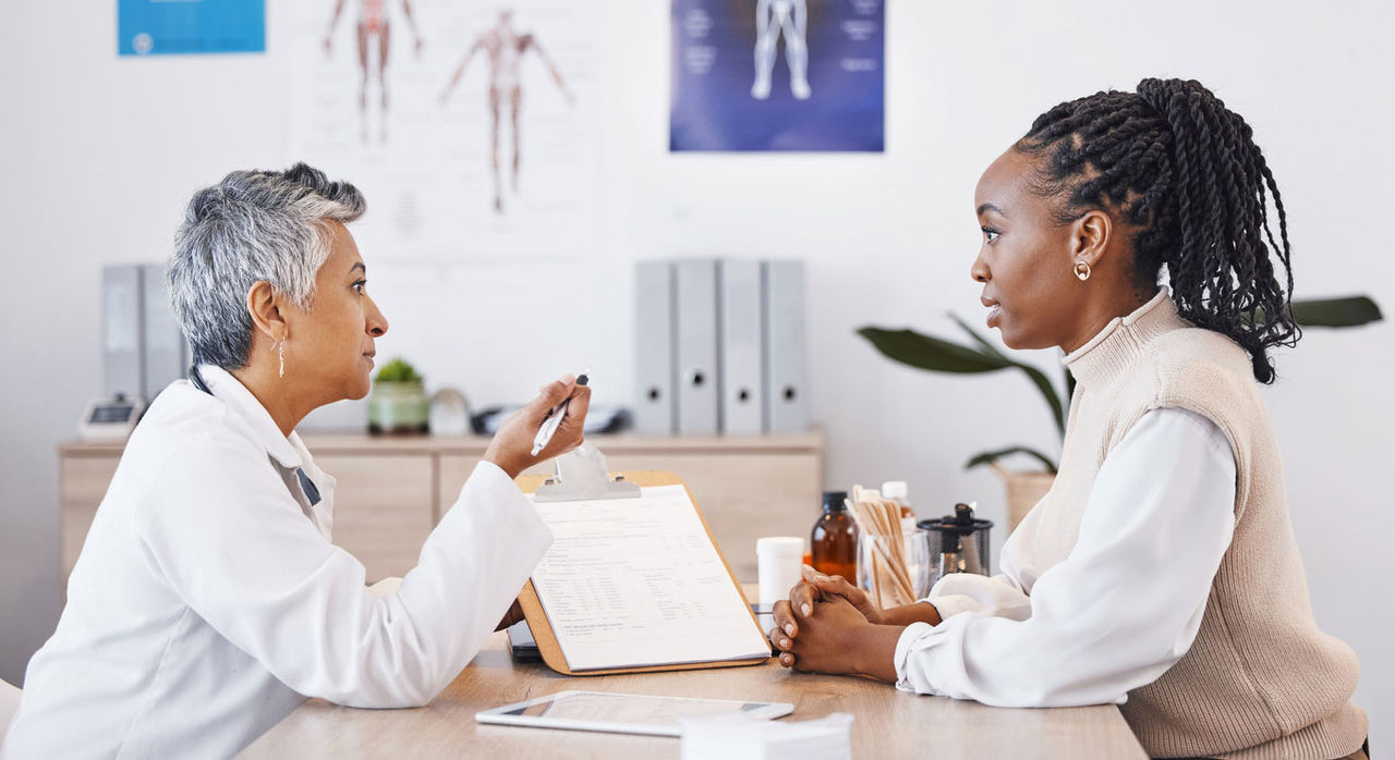 A Black woman speaks with her doctor.