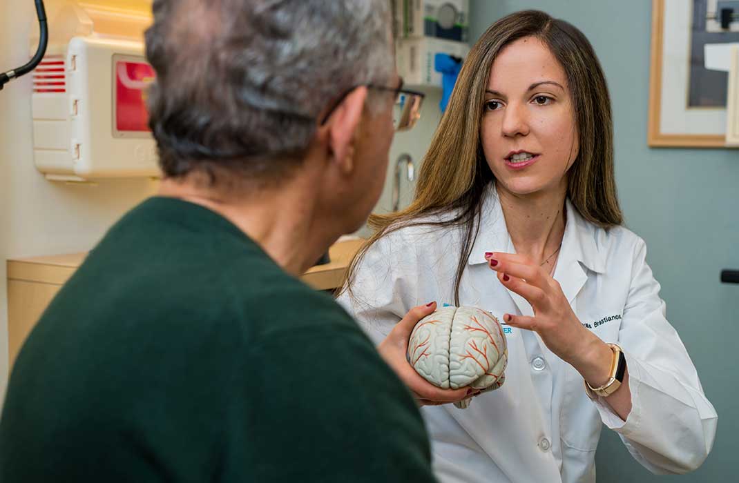 Dr. Priscilla Brastianos explains something to a patient, using a brain model to illustrate her point.