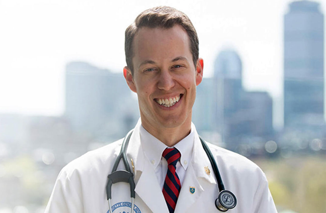 Brian Skotko, MD, MPP in lab coat and stethoscope, with the Boston skyline in the background.