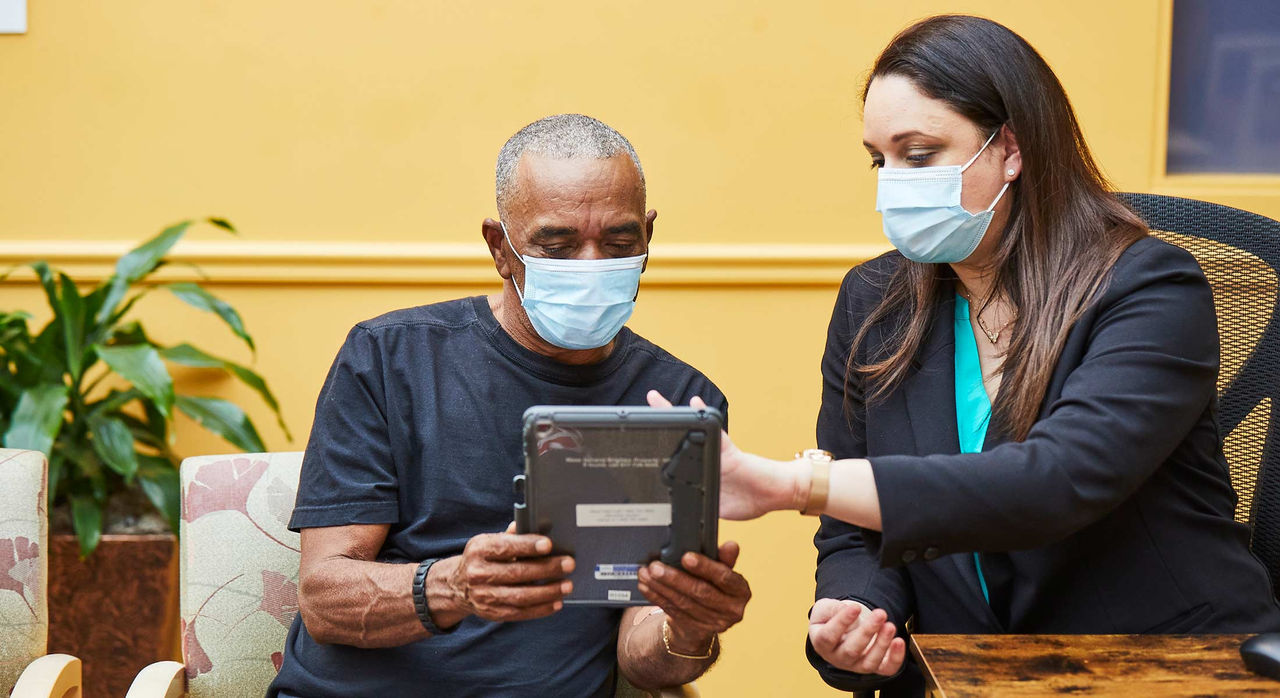 healthcare professional assisting patient in their use of a tablet