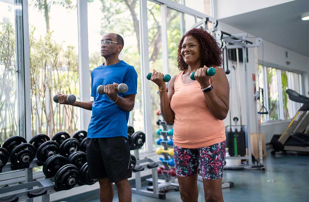 Two patients in workout clothes using hand weights in a gym.