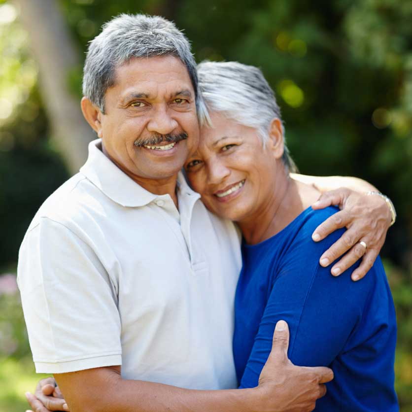 An older couple hug outdoors.