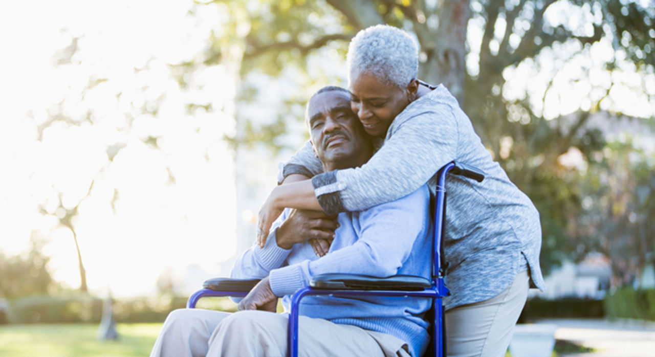 Caregiver hugs husband in wheelchair