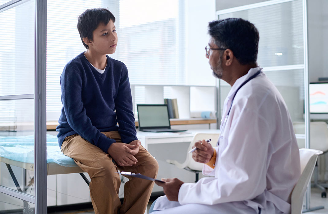 A doctor chats with a preteen in an examination room