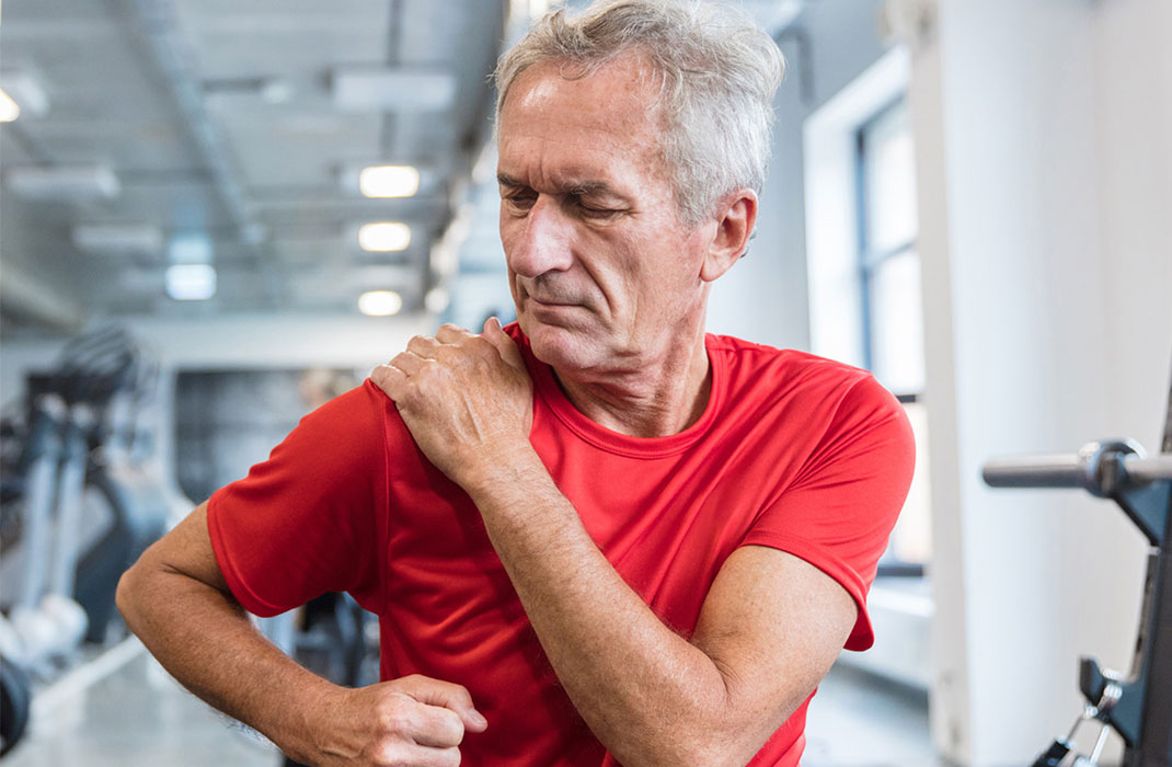 Man experiencing front shoulder pain at gym 