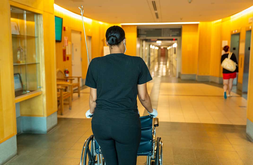woman pushing wheelchair in hospital hallway