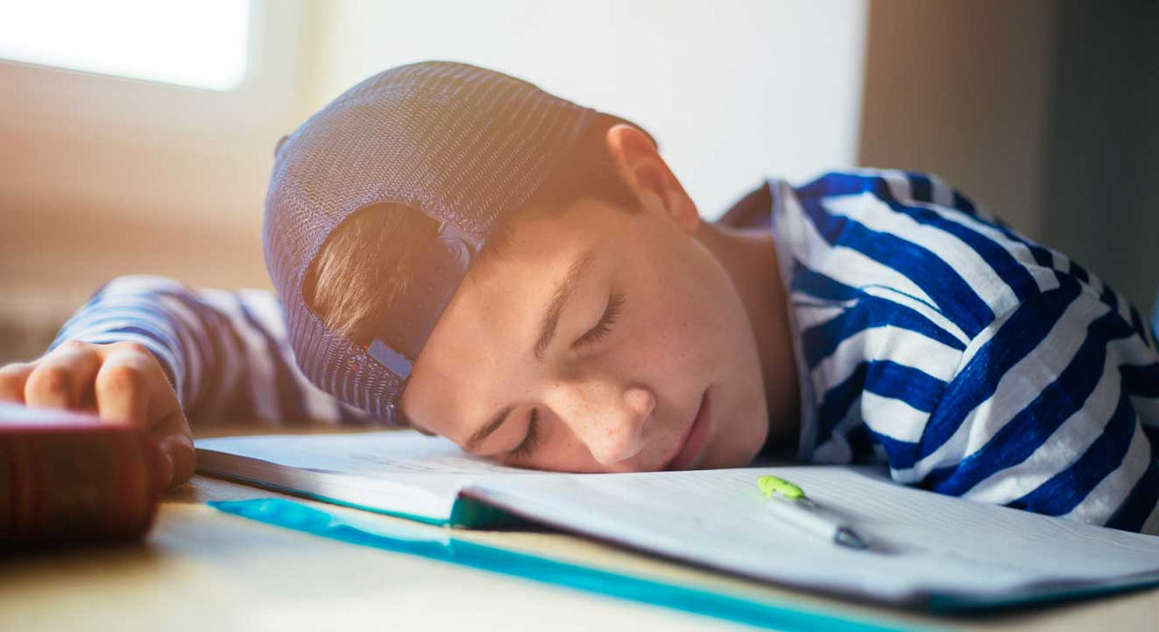 Teen falling asleep over his homework.