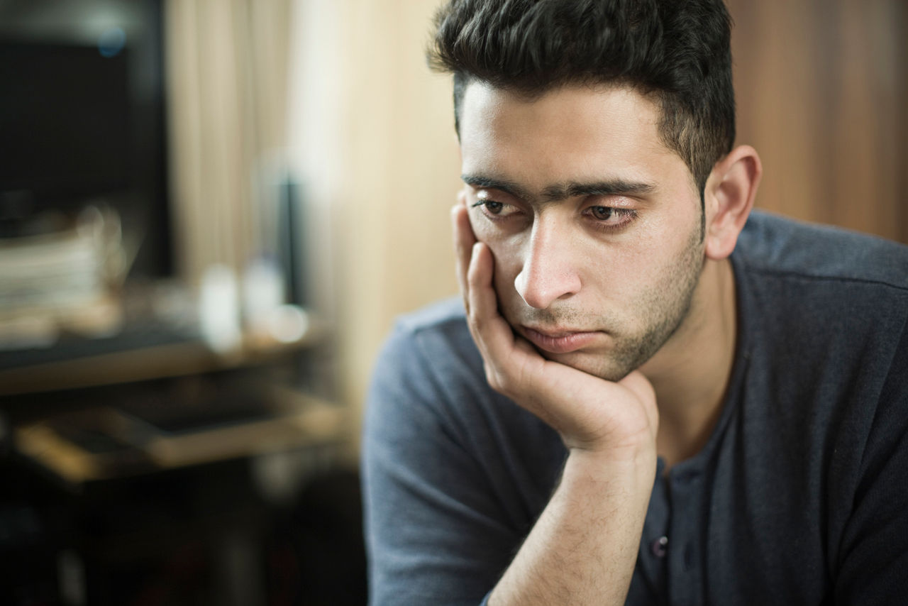 A man looks depressed at home.