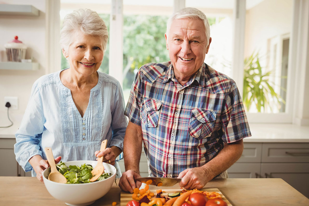 Couple prepares salad and vegetables in kitchen. These types of anti-inflammatory foods can help reduce arthritis joint pain.