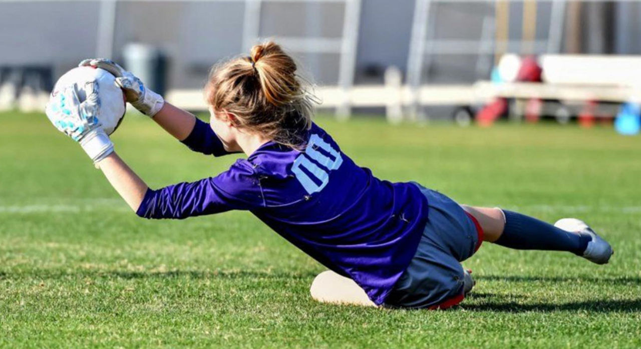 girl on soccer field catching soccer ball