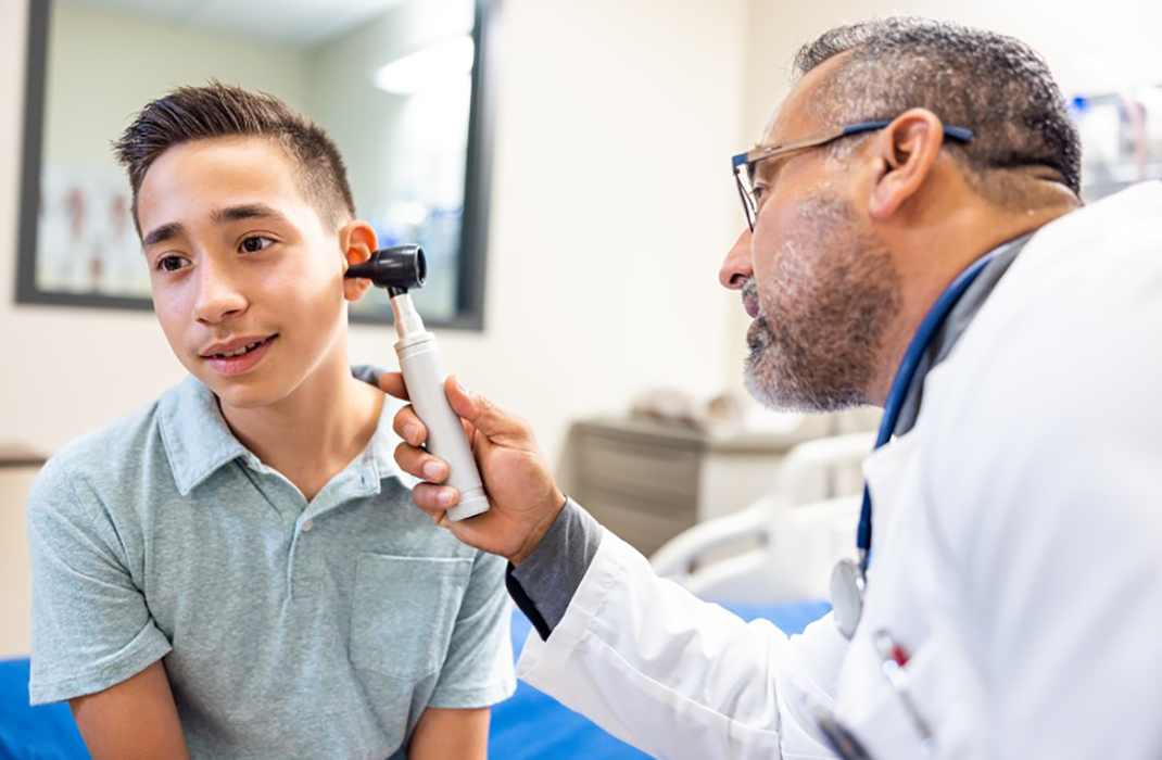 A doctor looks in a boy's ear.