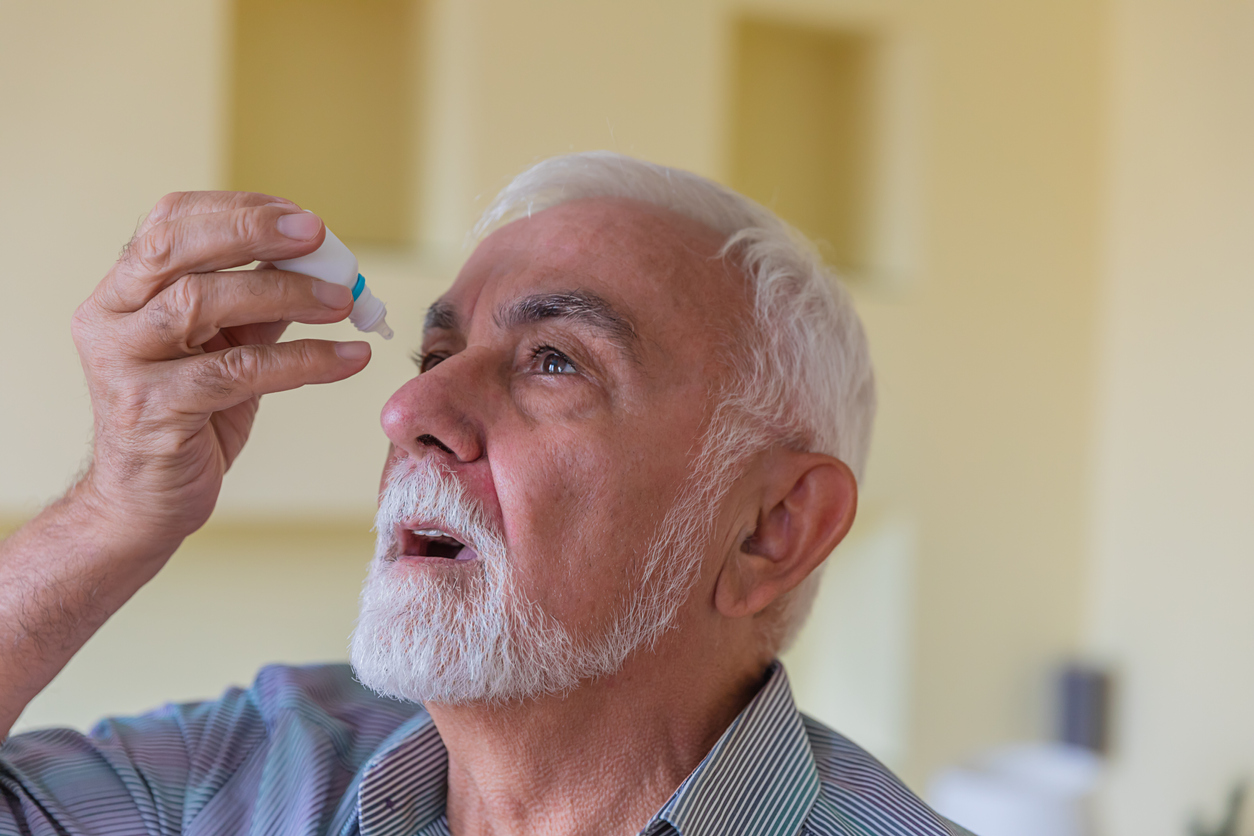 A man applying glaucoma eyedrops. 