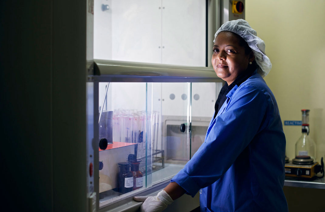 Female lab worker wearing cap, coat, and gloves