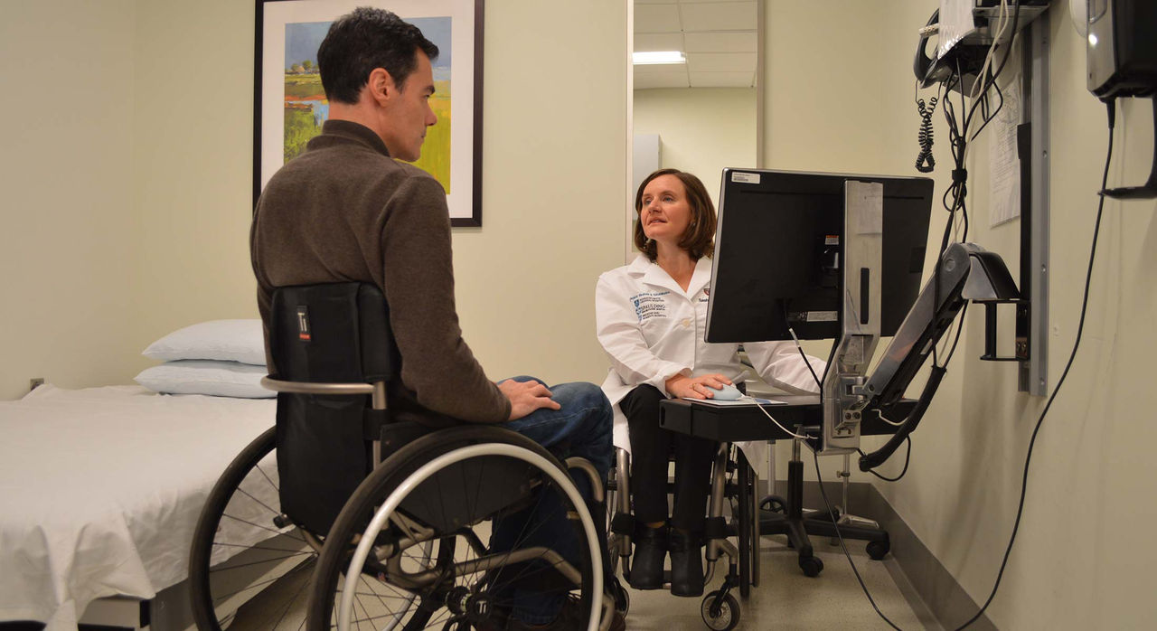 Dr. Cheri Blauwet and a patient, both in wheelchairs, in a medical examination room for a doctor-patient consult