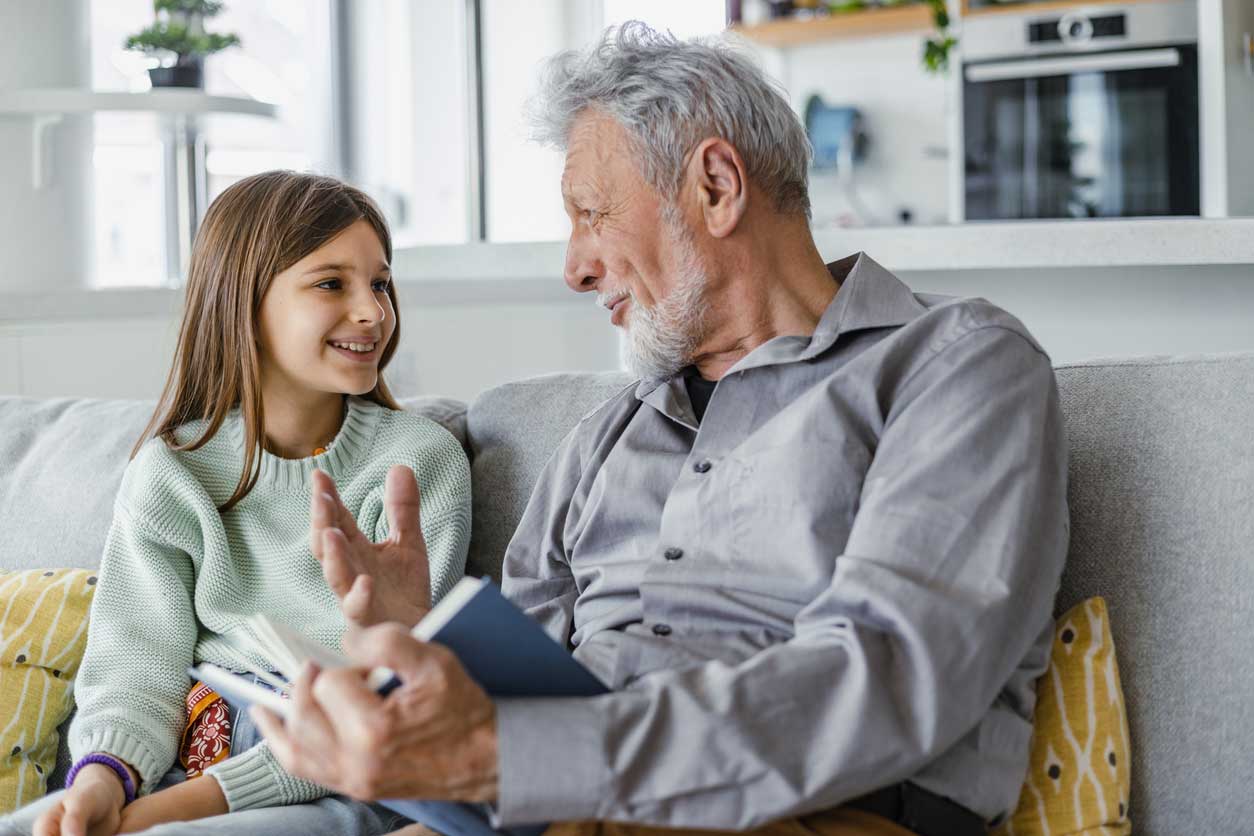 A grandfather reads to his granddaughter.